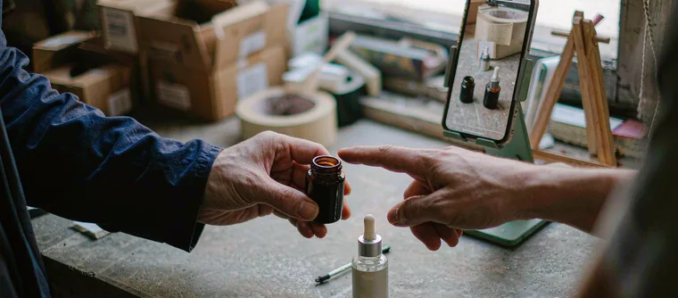 A hand arranging product packaging beside a phone playing a vertical product video